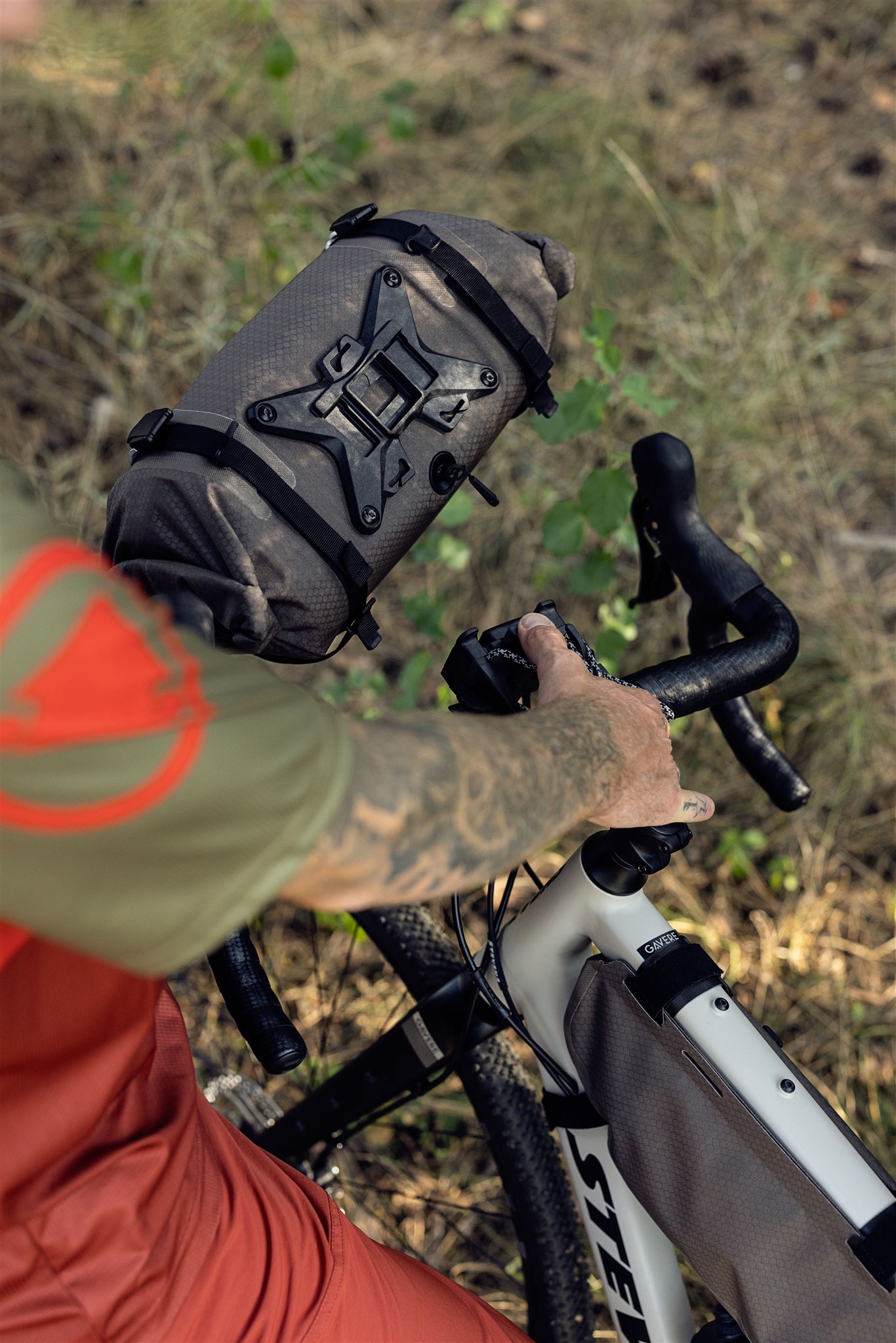 Cyclist riding with ORTLIEB Handlebar-Pack Flex in dark-sand on forest path