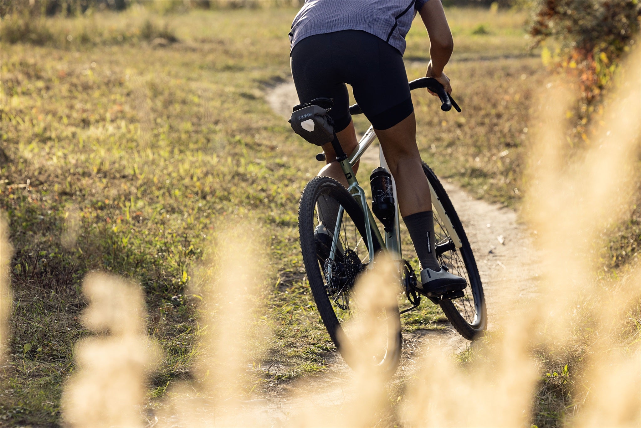 Cyclist with ORTLIEB Micro-Bag in dark-sand on gravel path in nature